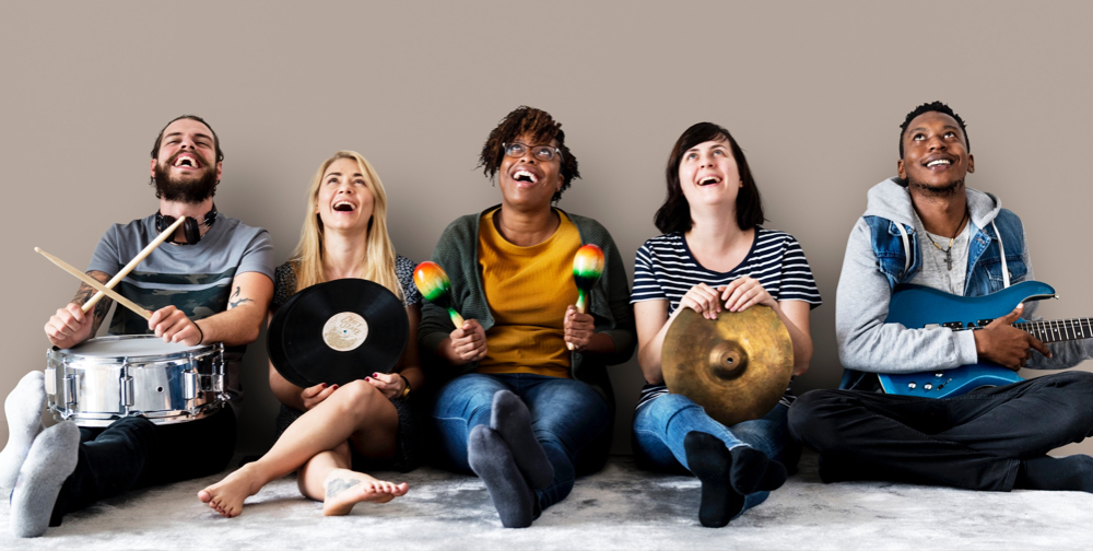 Young Adults holding musical instruments and smiling.