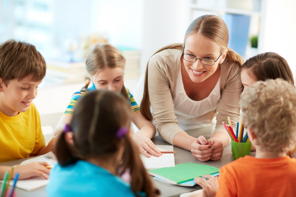 teacher helping students and smiling