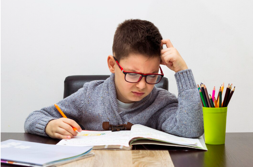 boy with dysgraphia looking puzzled at his textbook