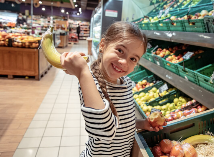 child holding fruit in a grocery store