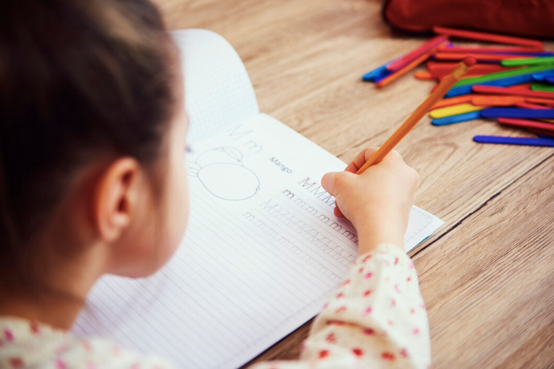 girl practising handwriting in a workbook