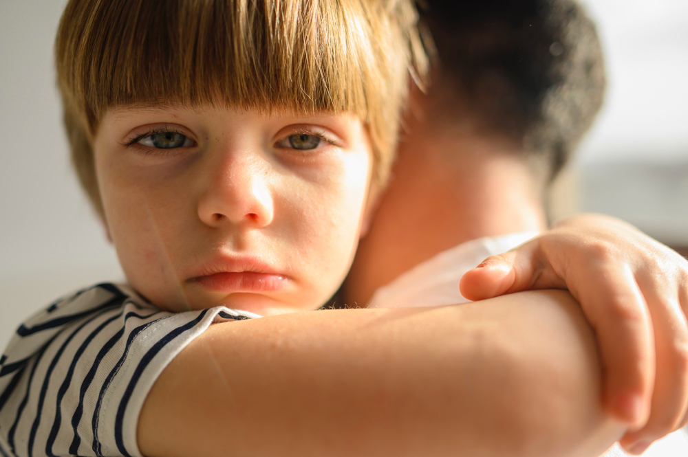 Sad little boy being held by his father