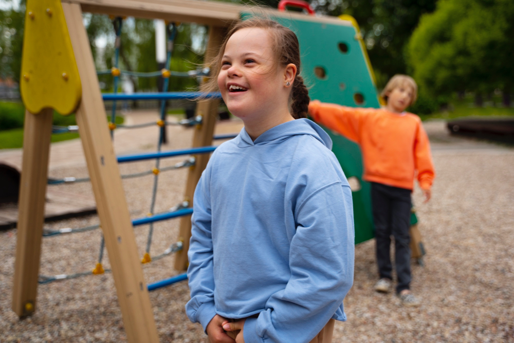 girl with Down syndrome smiling and playing in the park